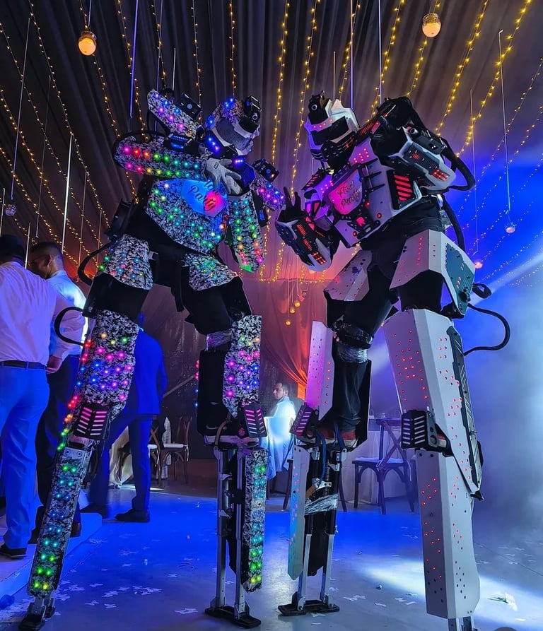Illuminated robot statues with colorful LED lights under a starry ceiling in a dark exhibition space